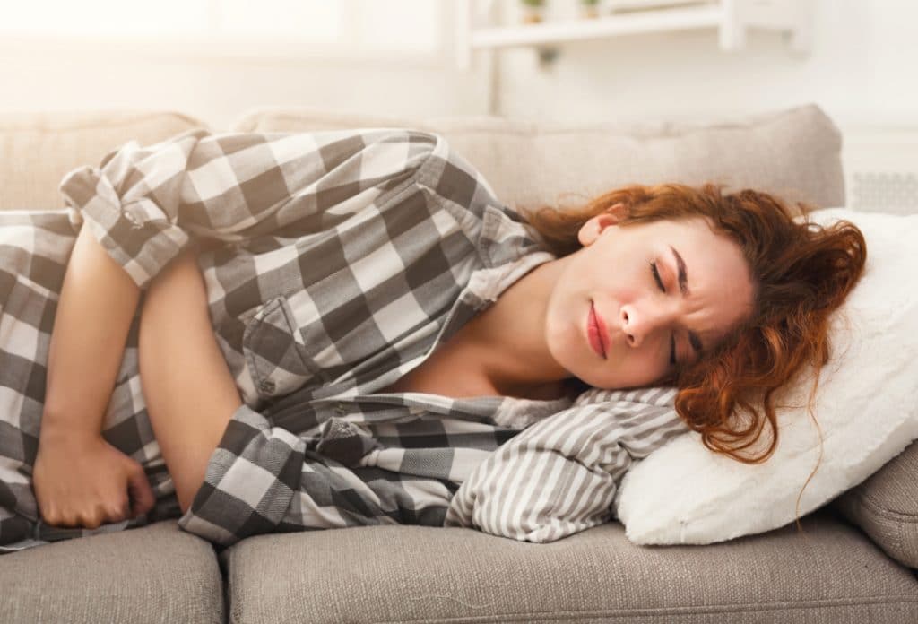 Woman laying down in pain holding stomach